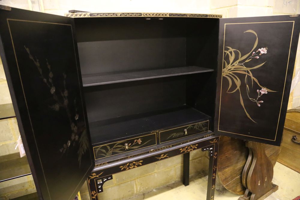 A Chinese black-lacquered and painted cabinet on stand, width 106cm, depth 46cm, height 173cm